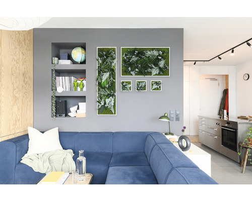 Obývací pokoj s modrou pohovkou a nástěnnou dekorací z rostlinných obrazů