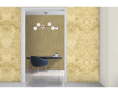 Je vidět světlá místnost se vzorovanou tapetou a psací stůl se židlí.