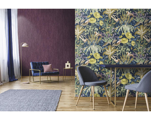 Obývací pokoj s vzorovanou tapetou, křeslem, stolem a kobercem na dřevěné podlaze.