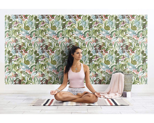 Žena medituje před stěnou s tapetou džungle ve světlé místnosti