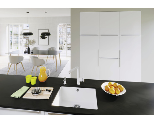 Světlá jídelna s jídelním stolem, židlemi, závěsnými lampami a kuchyňským dřezem na pracovní desce