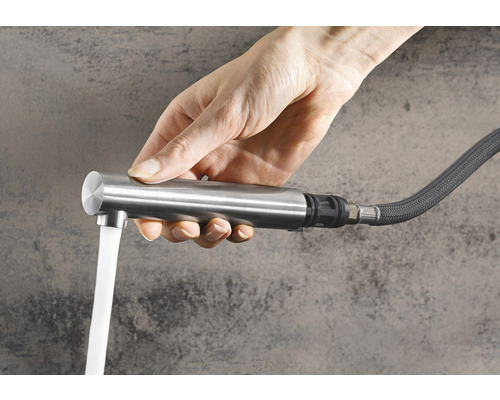 Ruka drží vodovodní kohoutek s tekoucí vodou