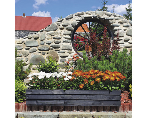 Květináč s květinami před zdí s dekorací kola