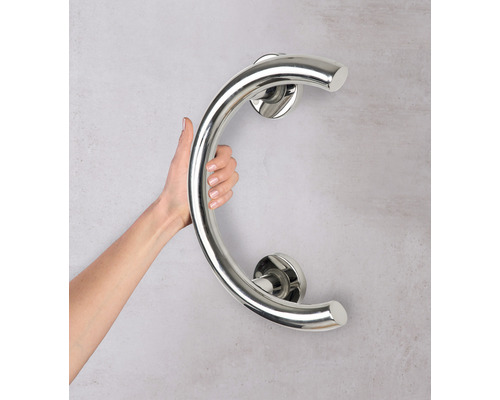 Osoba drží ohnuté madlo z nerezové oceli na zdi.