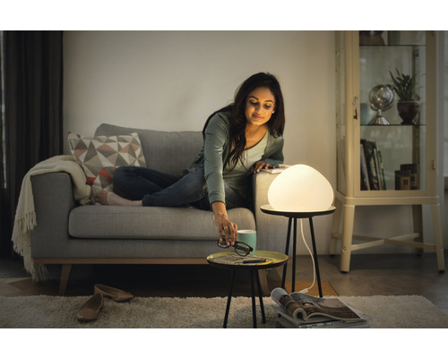 Žena na pohovce s lampou na stolku v obývacím pokoji