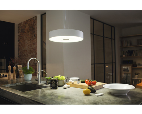Moderní kuchyně s kulatým závěsným svítidlem nad pracovní deskou s potravinami.