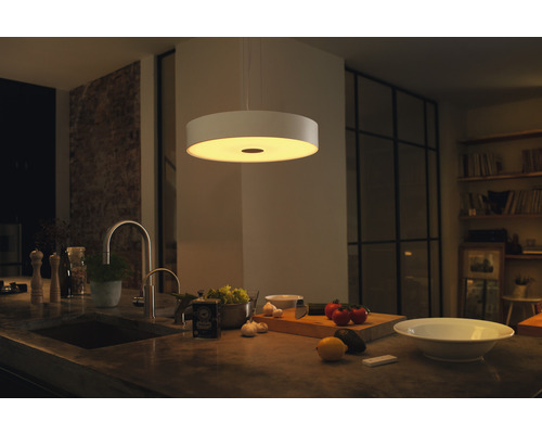 Moderní kuchyně s kulatým stropním svítidlem, dřezem a čerstvými surovinami na pracovní desce