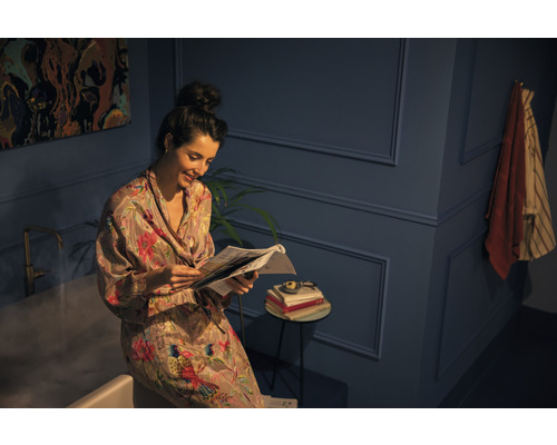 Žena čte noviny v koupelně s vanou a odkládacím stolkem