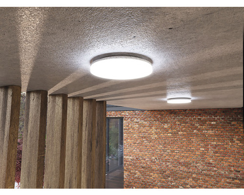 Dvě kulatá stropní svítidla v místnosti s cihlovou zdí a dřevěnými vzpěrami