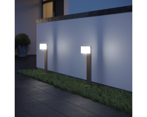 Dvě zahradní svítidla osvětlují cestu a trávník před zdí.