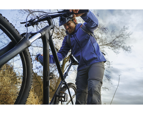 Muž tlačí černé horské kolo do kopce