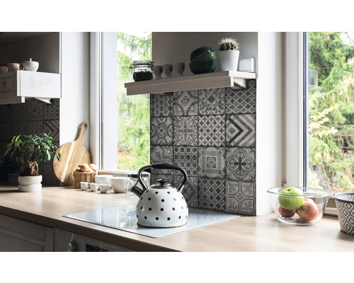 Kuchyňská scéna s pracovní deskou, dřezem, čajovou konvicí a obkládačkami v designu patchwork.