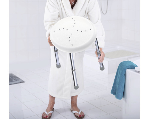 Žena v županu drží sprchovou stoličku s výškově nastavitelnýma nohama