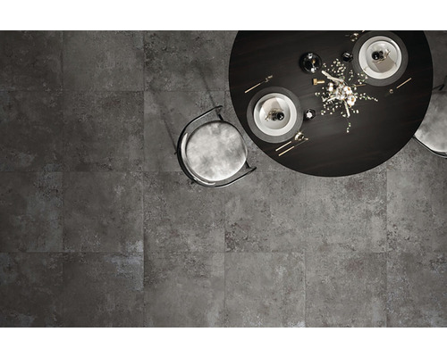 Pohled shora na šedou dlažbu s jídelním stolem a židlí