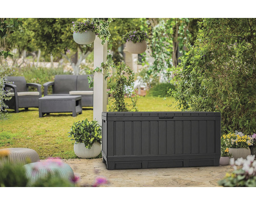 Záběr ze zahrady s úložným boxem, sedací soupravou a závěsnými květináči.