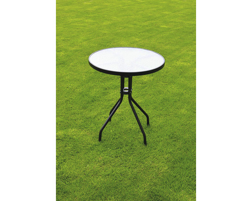 Kulatý zahradní stůl se skleněnou deskou a kovovým rámem na trávníku