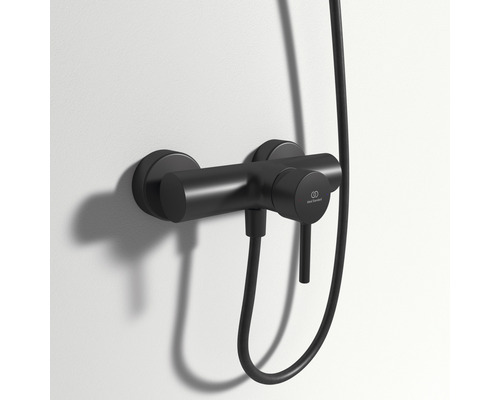 Černá sprchová baterie s hadicí sprchy namontovaná na zdi