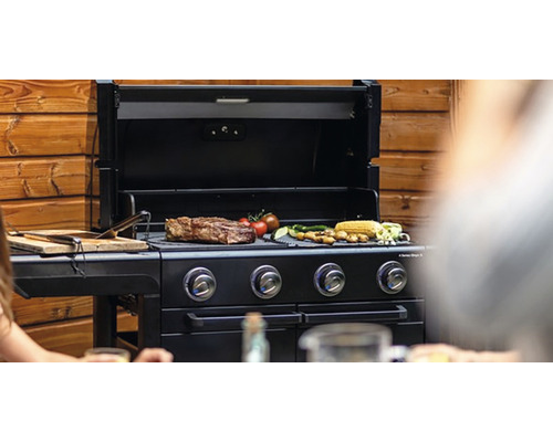 Plynový gril se steakem, zeleninou a kukuřičnými klasy na grilovací mřížce