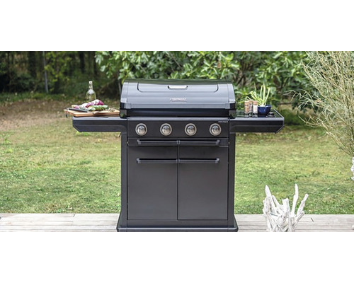 Tmavý plynový gril se čtyřmi hořáky venku s policemi