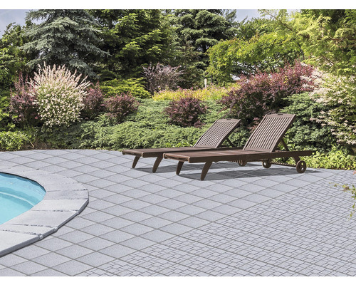 Terasa s kamennými deskami a dvěma lehátky v zahradě.