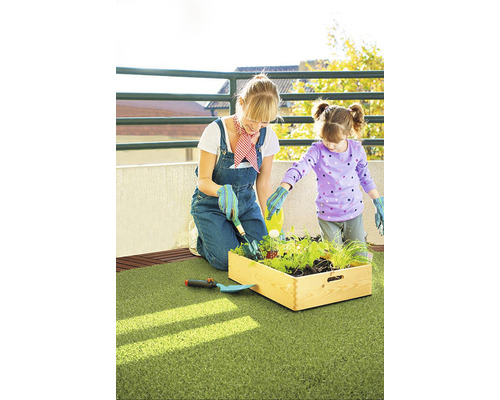 Žena a dítě sázejí vyvýšený záhon na balkoně s umělým trávníkem