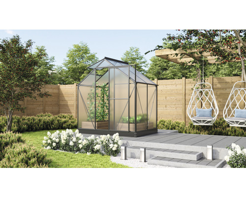 Skleník v zahradě s rostlinami a posezením.