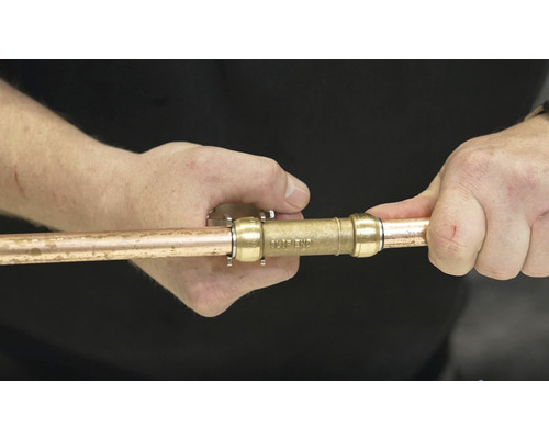 Osoba připojuje měděnou trubku ke konektoru.