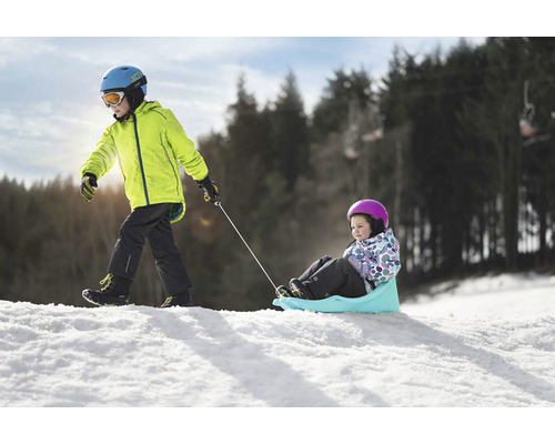 Chlapec táhne dívku na saních ve sněhu