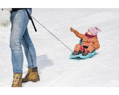 Dítě sedí na saních a je taženo osobou.