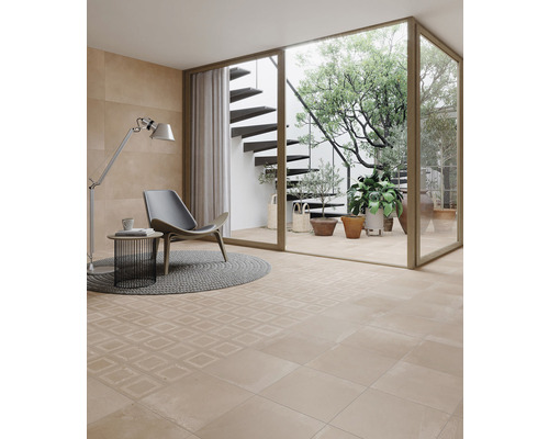 Světlá místnost s podlahovými dlaždicemi, křeslem a výhledem do zahrady se schodištěm