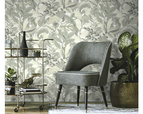 Scéna s květinovou tapetou, křeslem a barovým vozíkem.