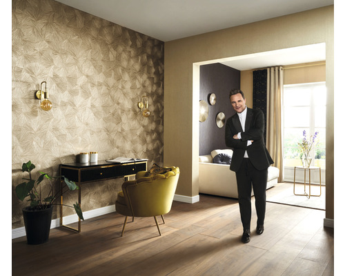 Obývací pokoj s tapetou se vzorem, psacím stolem, křeslem a osobou