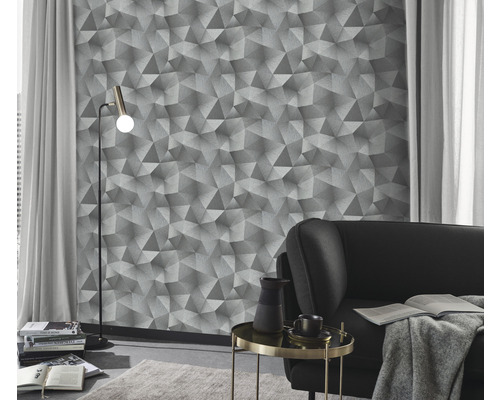 Obývací pokoj s geometrickou tapetou, stojací lampou a pohovkou.
