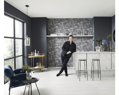 Světlá místnost s barem, stoličkami, křeslem, odkládacím stolkem a mužem