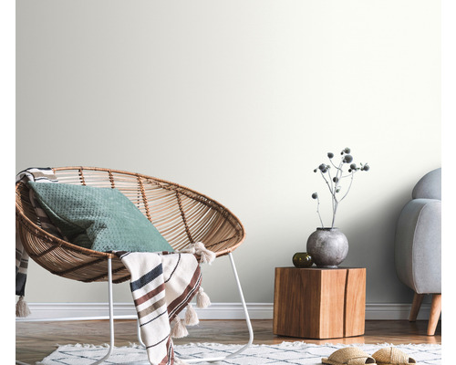 Dekorativní obývací pokoj s ratanovým křeslem, dřevěným stolem a světlými stěnami