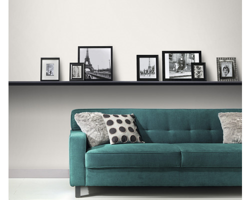 Moderní obývací pokoj s tyrkysovou pohovkou, polštáři a řadou fotorámečků na polici