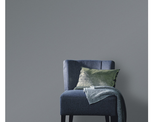 Jednobarevná tapeta za křeslem s polštářem a dekou