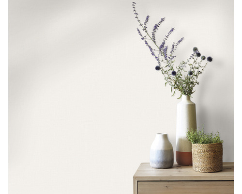 Dekorativní vázy s květinami na dřevěném stole před stěnou