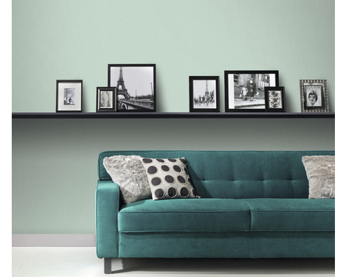 Obývací pokoj s policí, obrázky a zelenou pohovkou