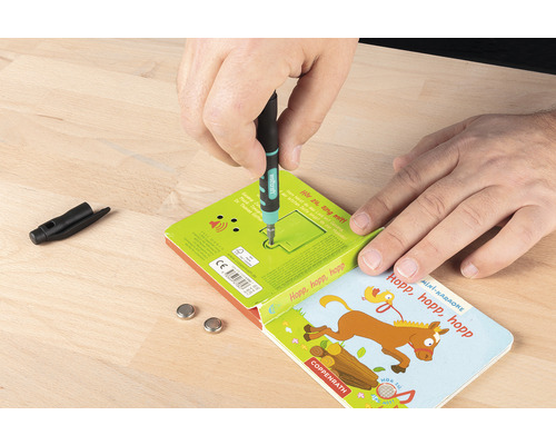 Muž vyměňuje baterie v dětské knize pomocí šroubováku.