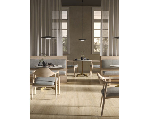 Interiérový pohled s stoly, židlemi, lavicemi a závěsnými svítidly ve světlé místnosti.