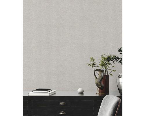 Světlá vzorovaná tapeta na zdi nad komodou.