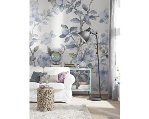 Zdobený obývací pokoj s pohovkou, příručním stolkem a stojací lampou před květinovou tapetou