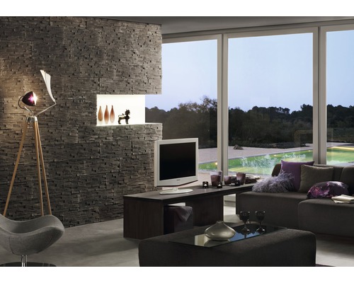 Obývací pokoj s kamennou zdí, televizí, lampou a okenní stěnou s výhledem do zeleně