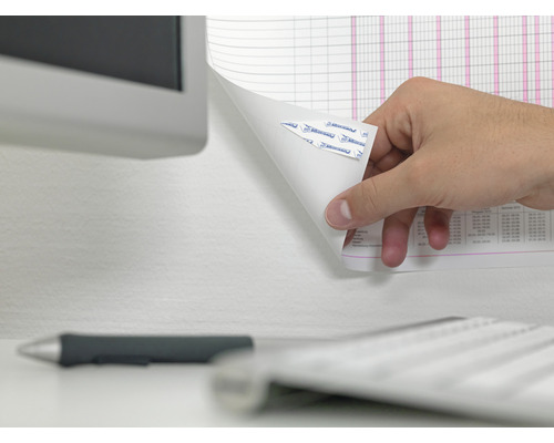 Ruka odstraňuje list papíru s lepicími proužky ze zdi