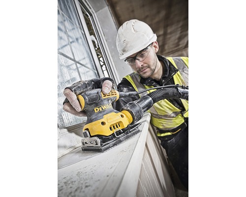 Řemeslník brousí okenní rám pomocí vibrační brusky DeWalt