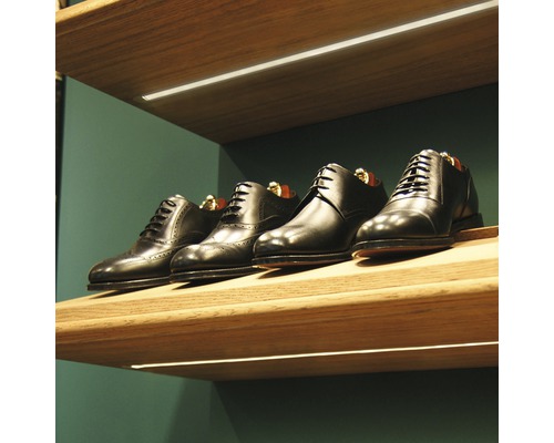 Řada černých kožených bot na dřevěné polici