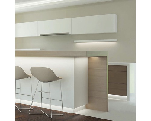 Světlá kuchyně s bílými závěsnými skříňkami, barovým pultem a dvěma barovými židlemi.