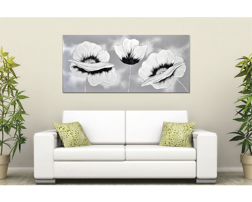 Dekorativní nástěnný obraz s květinovým motivem nad bílou pohovkou v světlé místnosti