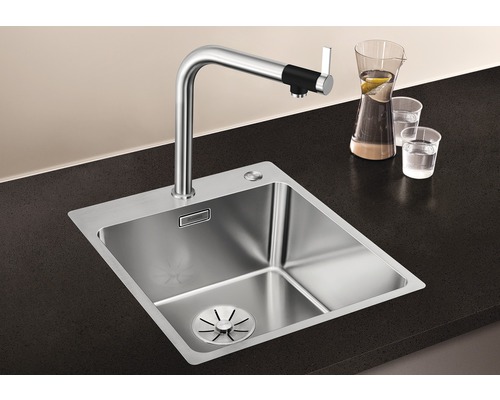 Nerezový dřez s vodovodní baterií na tmavé pracovní desce